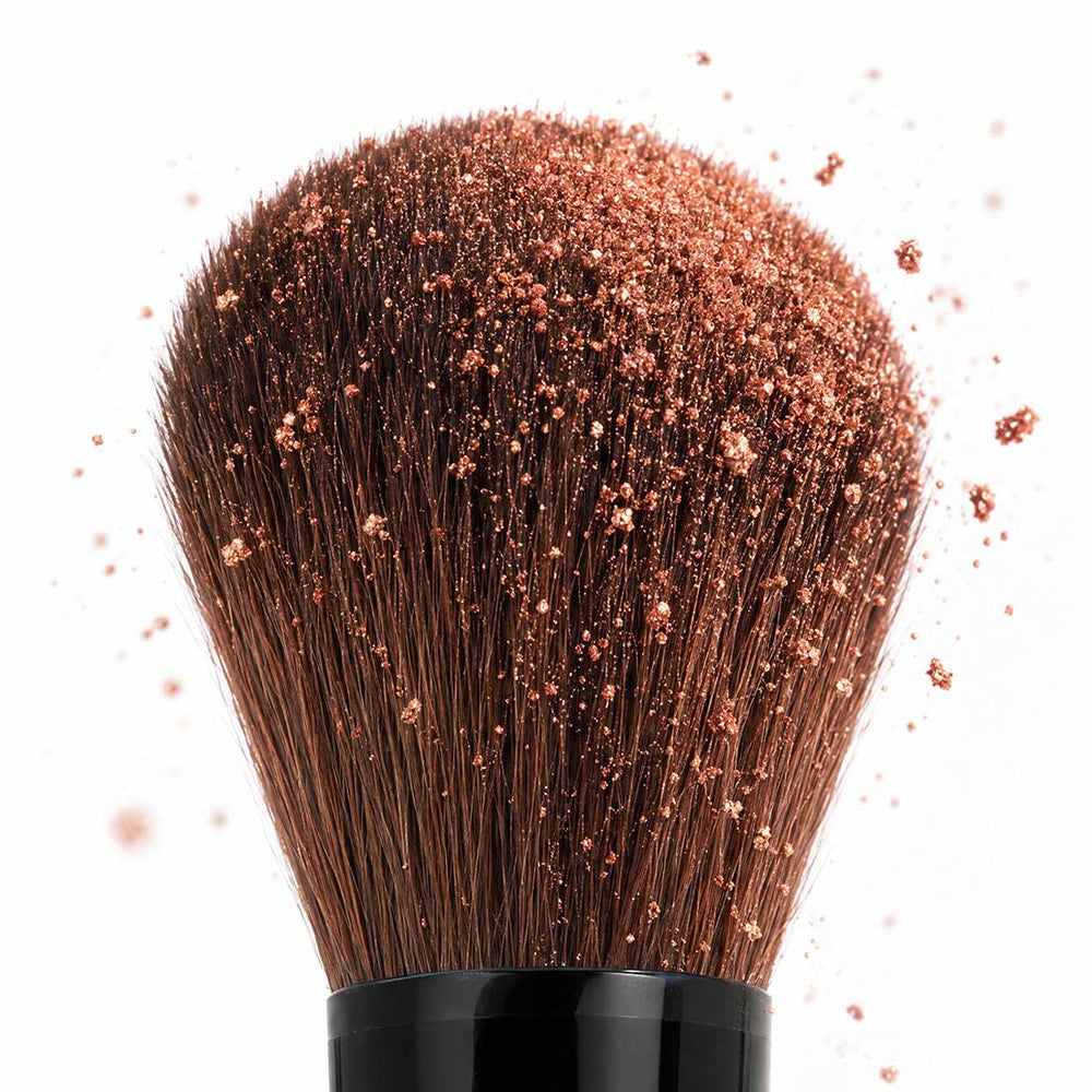 Close-up of the full blending end of the Palladio Dual Ended Brush covered with loose makeup powder.