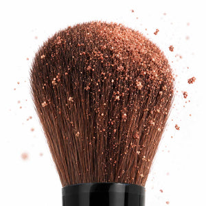 Close-up of the full blending end of the Palladio Dual Ended Brush covered with loose makeup powder.