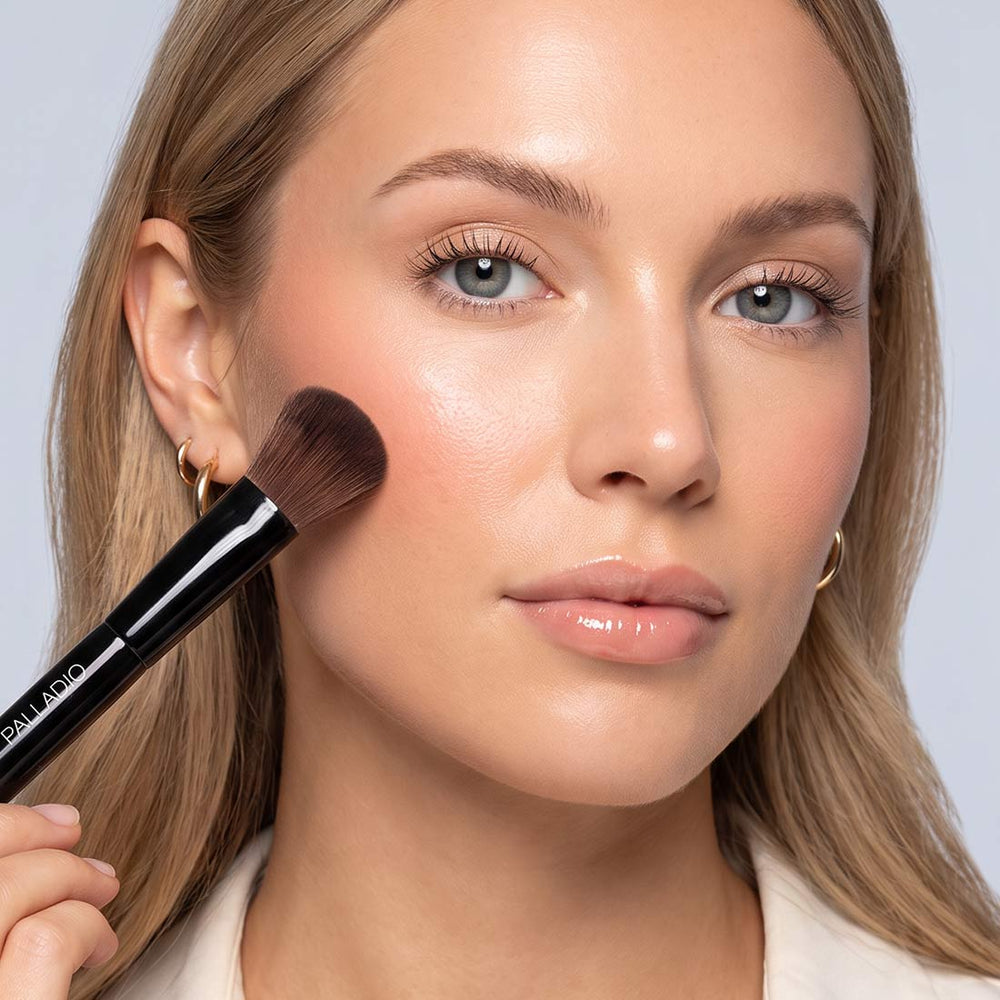 Model applying cheek color with the full blending end of the Palladio Dual Ended Brush.
